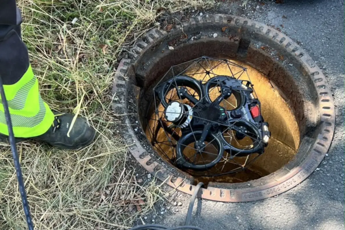 Inspektionsdrohne im geöffneten Kanalschacht, ein Techniker der RKS Rohr und Kanal Technik GmbH steht daneben